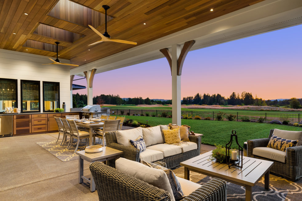 Covered Patio with Ceiling Fans and Outdoor Kitchen with large yard and field in the background