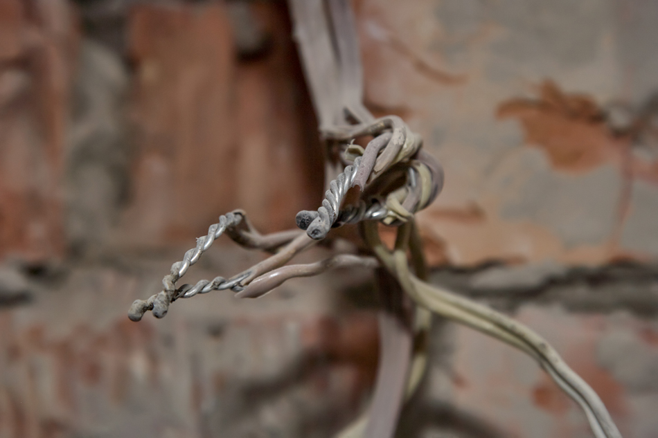 Old-electrical-aluminum-wires-connected-by-twisting-1679808690 Old electrical aluminum wires connected by twisting, hanging from wall.